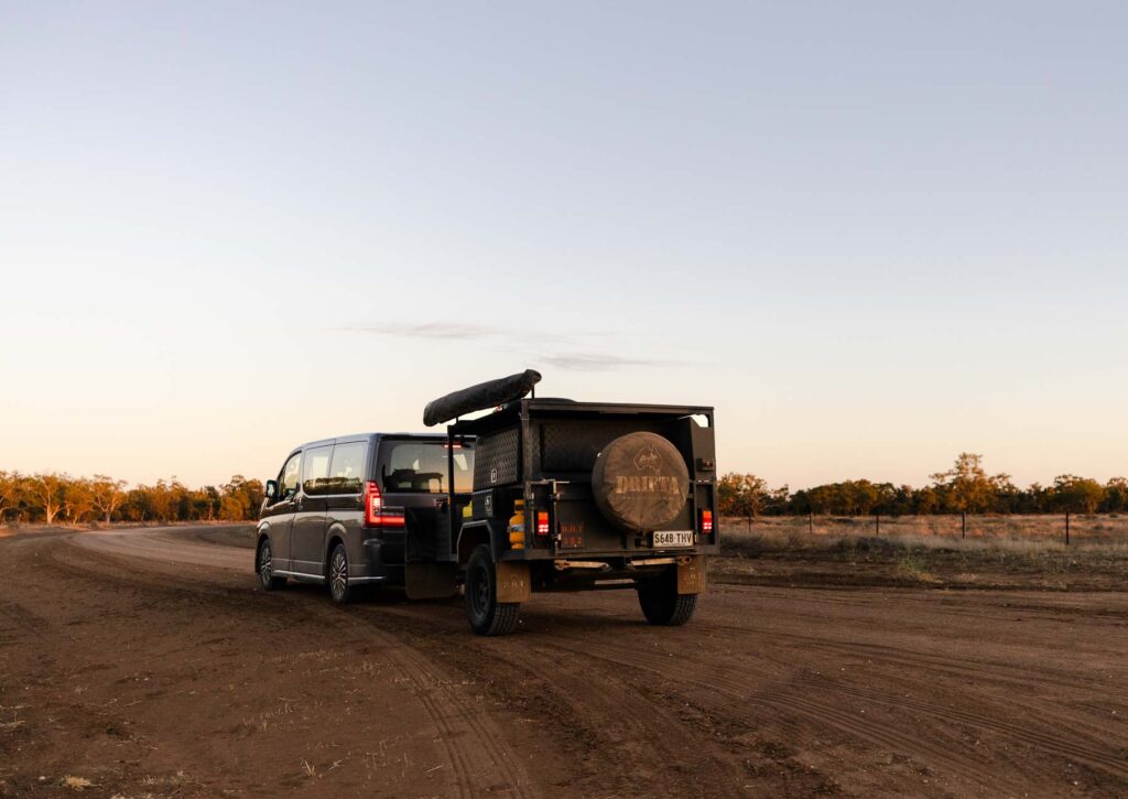 Tour van and trailer parked on a dirt road at Carinya Station at dusk