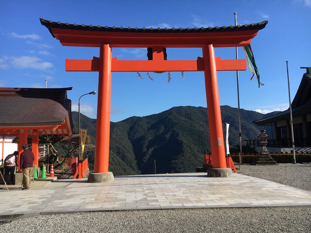 Red torii gate framing forested mountains at a Japanese shrine