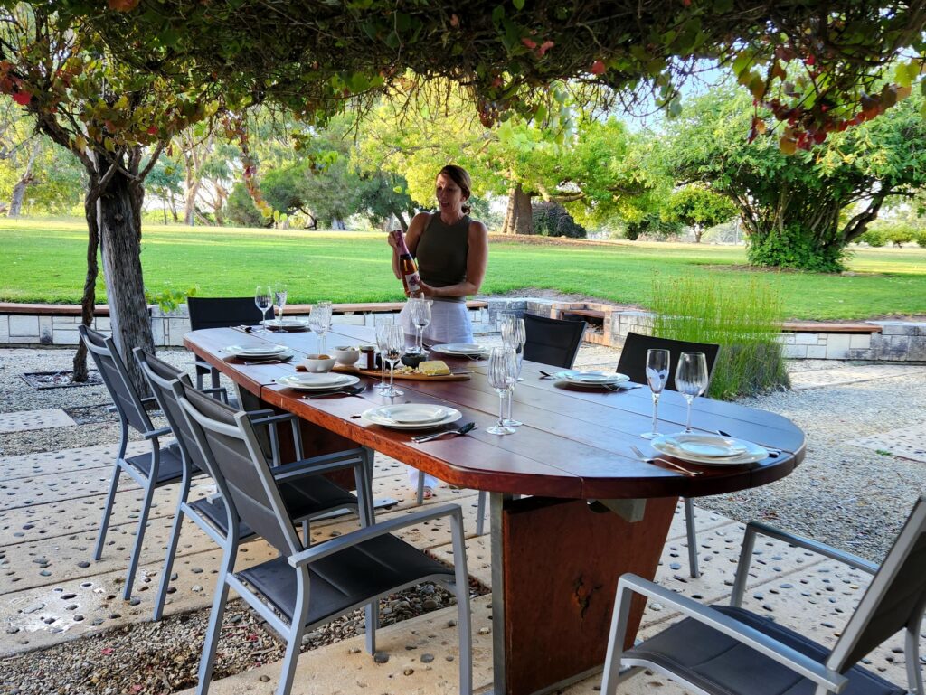 Outdoor dining table set beneath vines in a landscaped South Australian garden